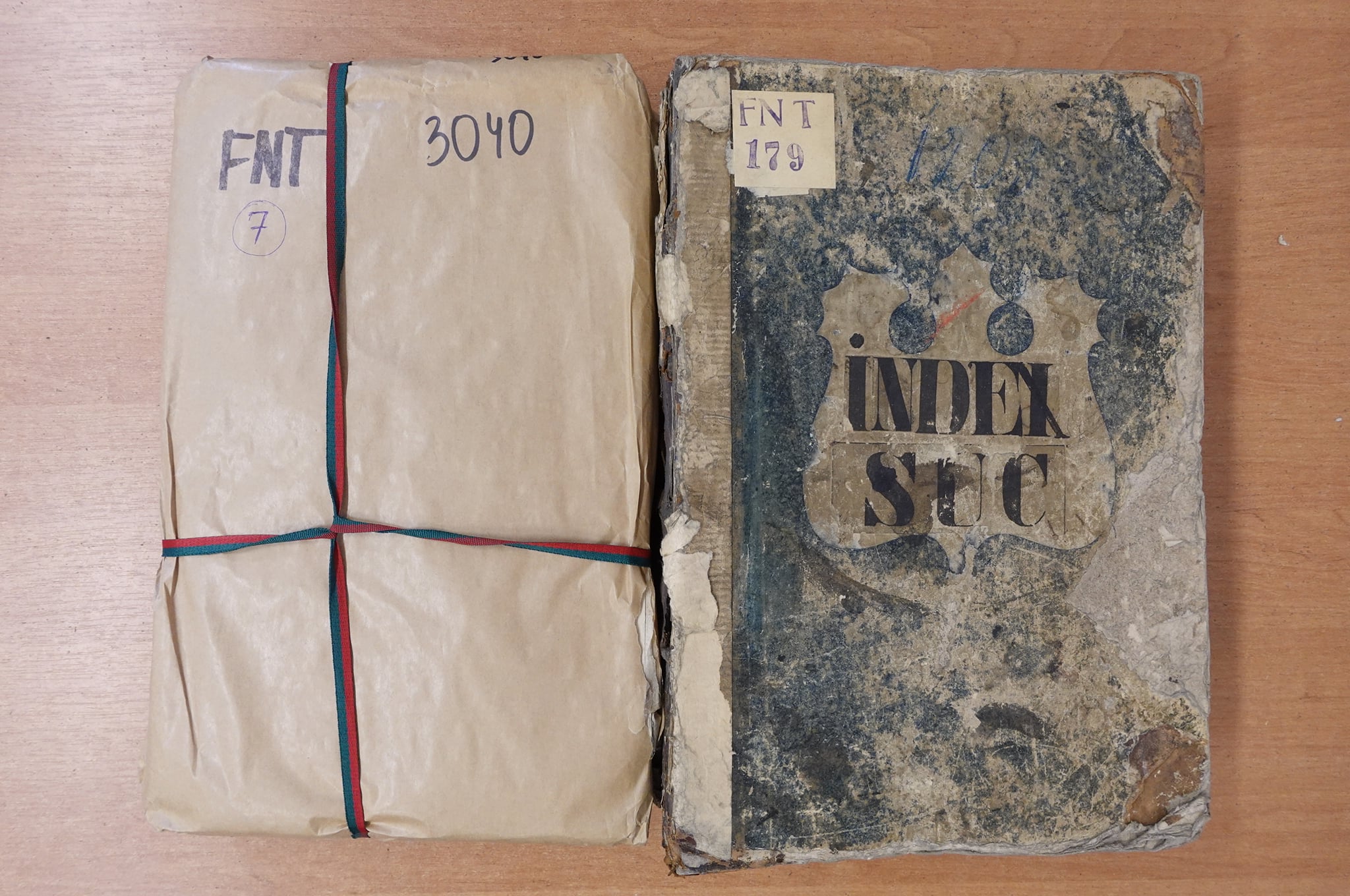 Two 18th-century nobility record volumes — one wrapped in archival paper tied with red and green ribbon, the other showing a worn cover with a heraldic "INDEX" shield.